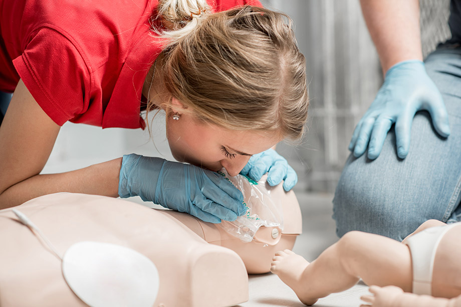 Person performing CPR in a classroom on a dummy